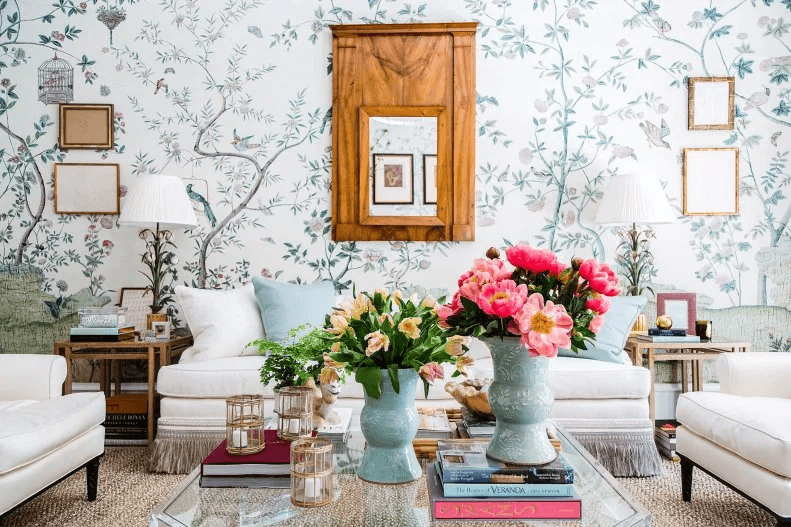 Wohnzimmer mit floraler Tapete, hellen Sofas, Blumenvasen und Holzmöbeln als Stilbeispiel