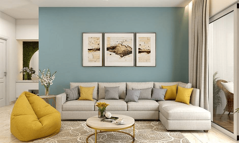 Helles Wohnzimmer mit hellblauer Wand, beigem Sofa, gelbem Sitzsack, rundem Couchtisch und Kunstdrucken