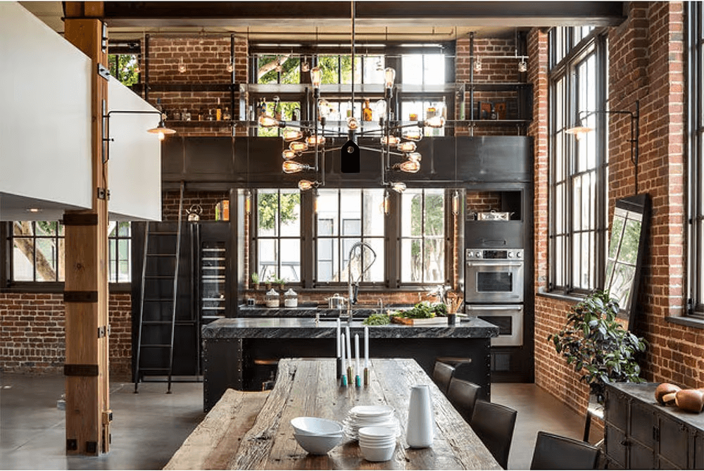 Loft im Industrial Style mit Ziegelwand, hohen Sprossenfenstern, langem Holztisch und Metallleuchte